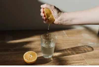 A man's hand squeezing a lemon and storing lemon juice in a glass to remove rust from can opener 