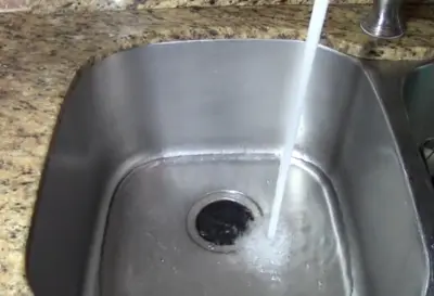 Sink tap is on and water is passing through garbage disposal hole
